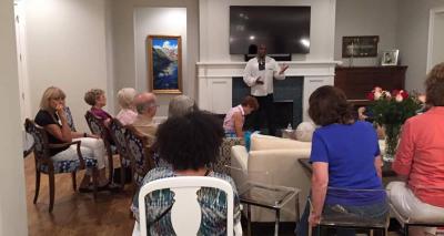 People seated in a living room listening to speaker.