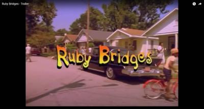 street scene from the movie Ruby Bridges showing a neighborhood with cars, people walking, and riding bikes