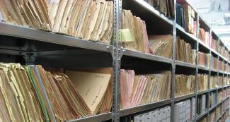 file folders and boxes on long row of metal library shelves