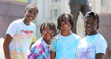 Four black youth in tie-dyed shirts smiling