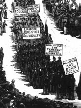 Illustration of people marching and carrying signs that say "All men are born equal," "Labor creates all wealth," and "Agitate Educate Organize" while crowds line the sides of the street.