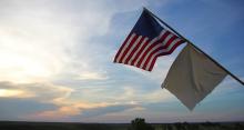 American flag with white flag below flying in the breeze.