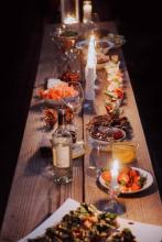 A long wooden table with lit candles and many serving dishes of food.